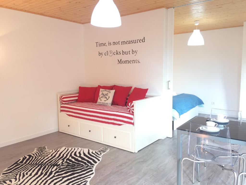 a room with a bed with red pillows and a table at Golden Halcyon - Ericeira Villas in Ericeira