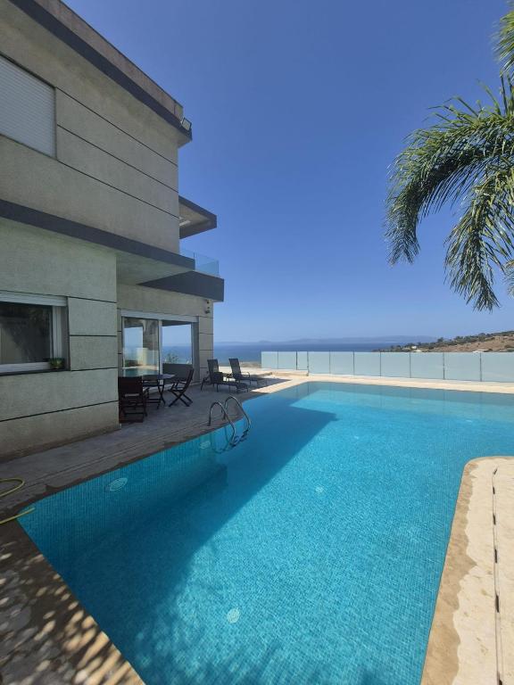 a swimming pool in front of a building with the ocean at Villa mnar 3 chambre en haut in Tangier