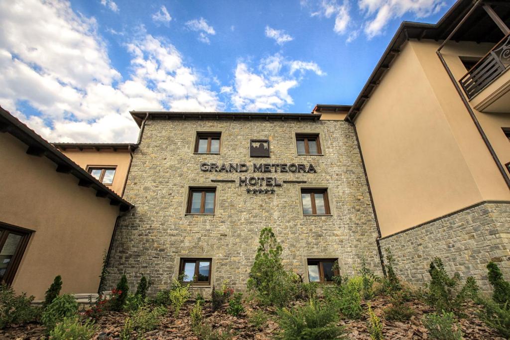 a building with a sign on the side of it at Grand Meteora Hotel in Kalabaka