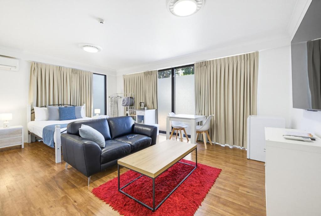 a hotel room with a bed and a couch and a table at Caloundra Affordable Beachside Studio in Caloundra
