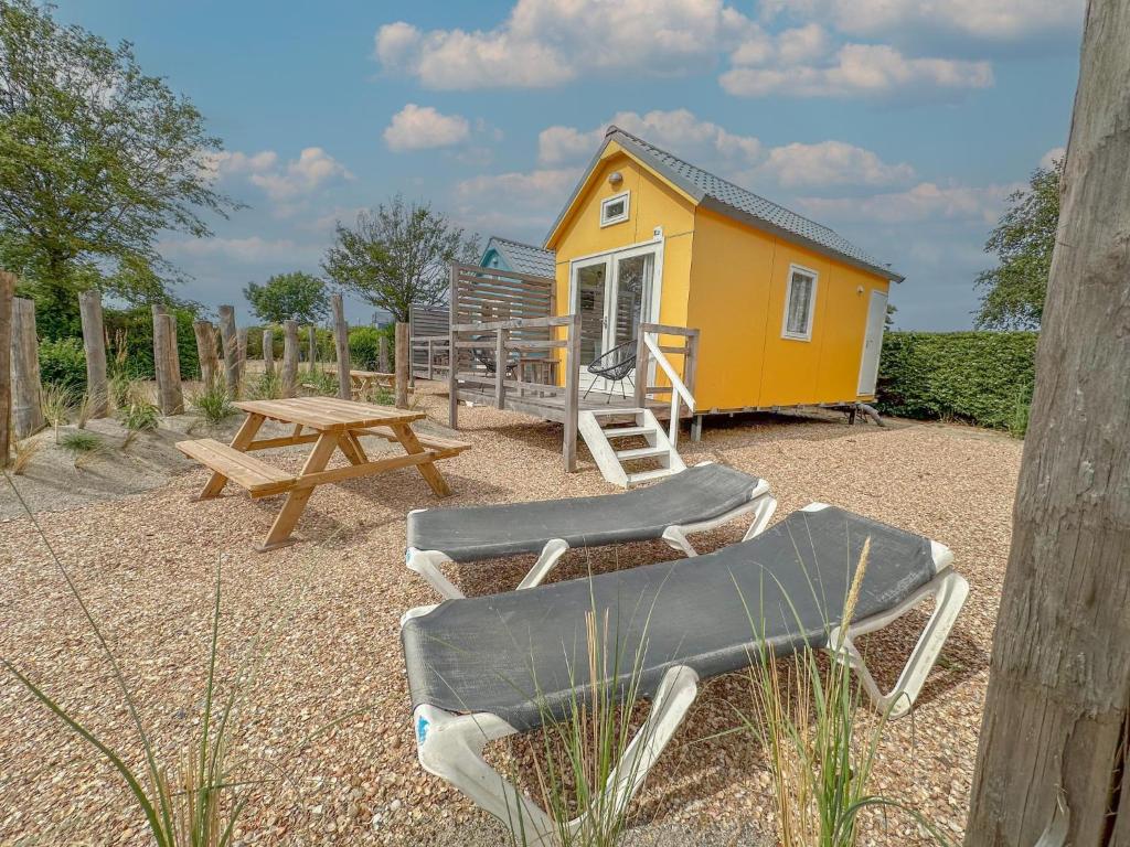a small yellow house with a picnic table and a bench at Yellow Bird in Ellemeet