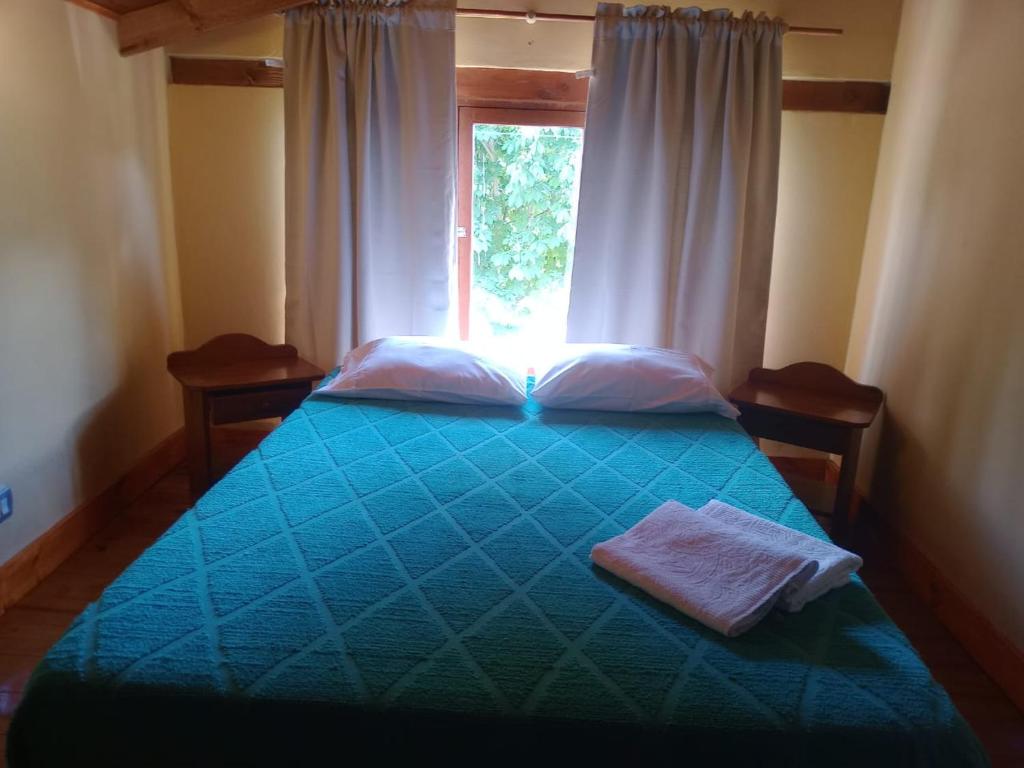 a bedroom with a blue bed with a window at La cabaña de ines in El Bolsón