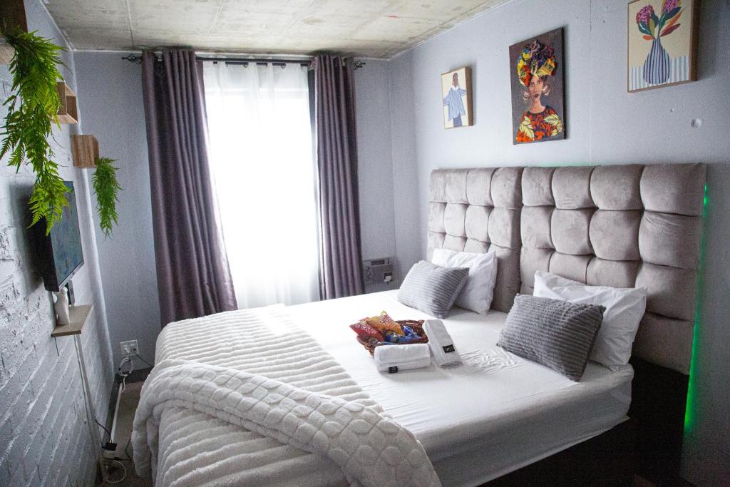 a bedroom with a large white bed with a large headboard at The Hideaway Studio-Maboneng in Johannesburg