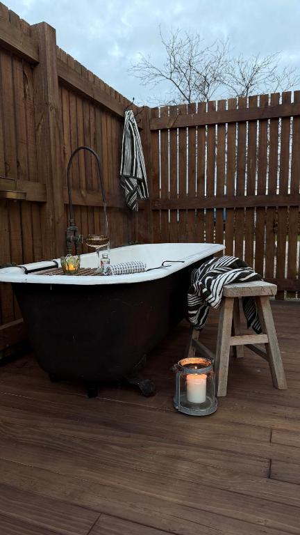 a bath tub sitting on a deck next to a fence at Gate Keepers Cottage in Tasman