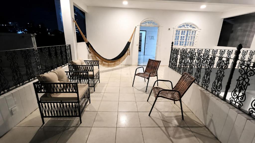 a balcony with chairs and a hammock in a room at Encantos do Mar Hostel in Recife