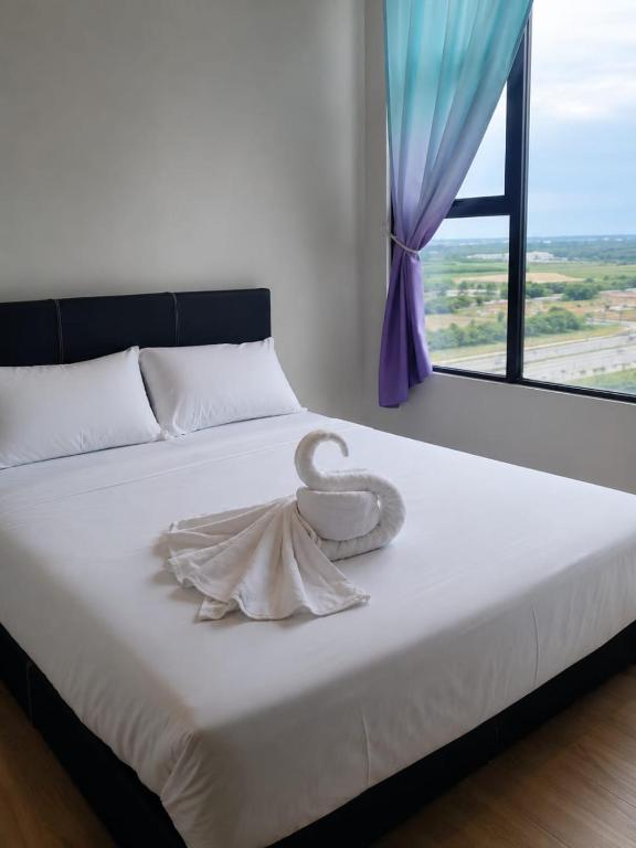 a bed with a towel on it with a window at CeeJay Suites in Penampang