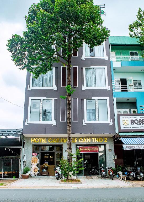 a tall building with a tree in front of it at Khách sạn Caravelle Cần Thơ 2 in Can Tho