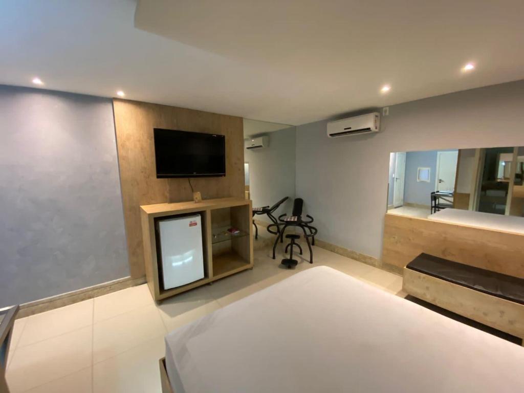 a living room with a tv and a room with a bed at Eros Motel Hotel in Caicó
