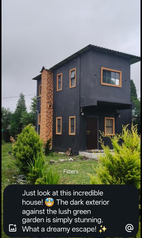 a black house with the wordsjust look at this integrated against the irish green at Rimaaia farm house in Lāitlyngkot
