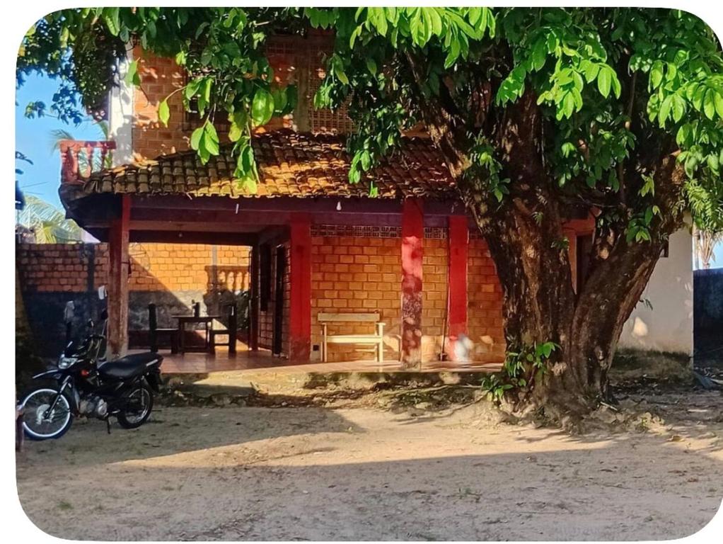 a motorcycle parked in front of a building with a tree at Wana Soeiro in Marapanim
