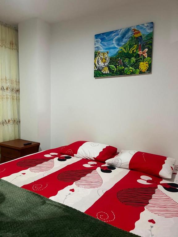a bed with a red and white blanket on it at Tayra Living Suites in Mocoa