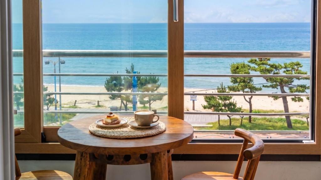 a table in front of a window with a view of the beach at Yangyang Verit Pension in Yangyang