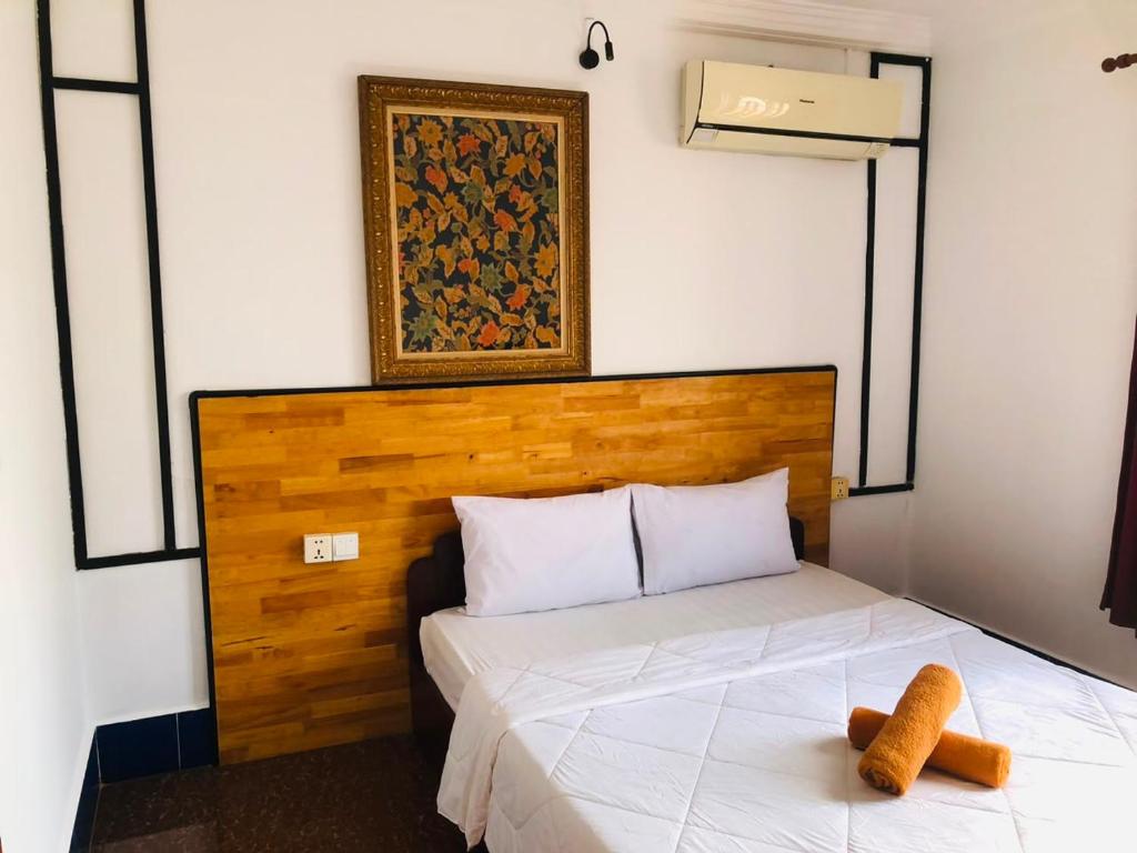 a bed with a wooden headboard in a room at Phum Angkor in Siem Reap