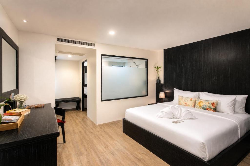 a bedroom with a large white bed and a desk at JALMIN Hotel Samui in Chaweng