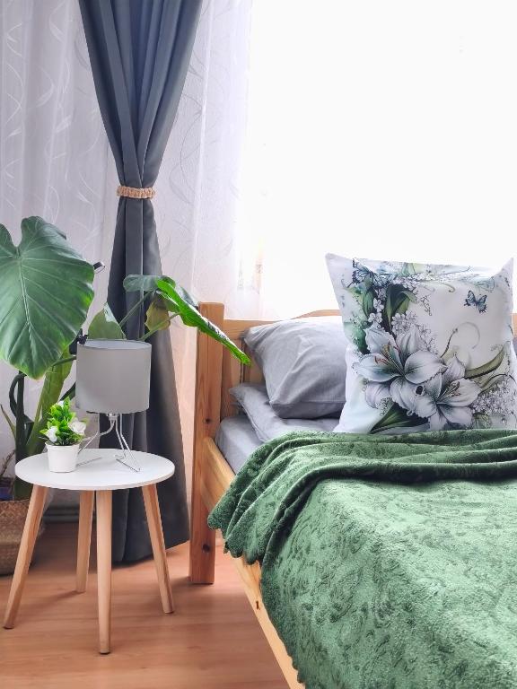 a bedroom with a bed with a green blanket and a table at Родопско сърце in Chepelare