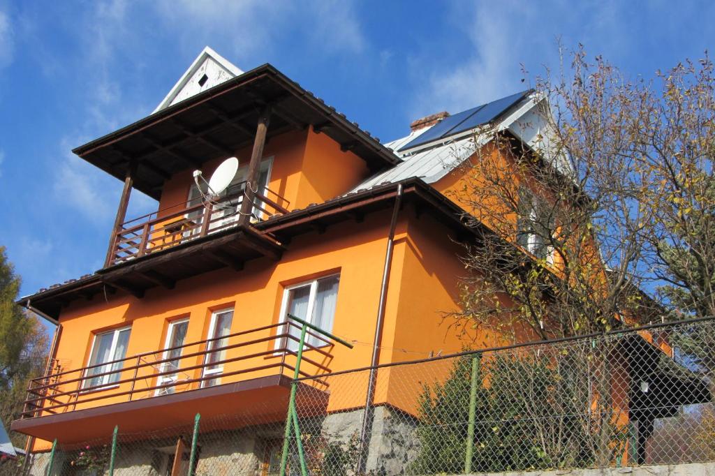 une maison orange avec un balcon au-dessus dans l'établissement "Nad Zdrojami" Pokoje Kowalczyk 691-739-603, à Szczawnica