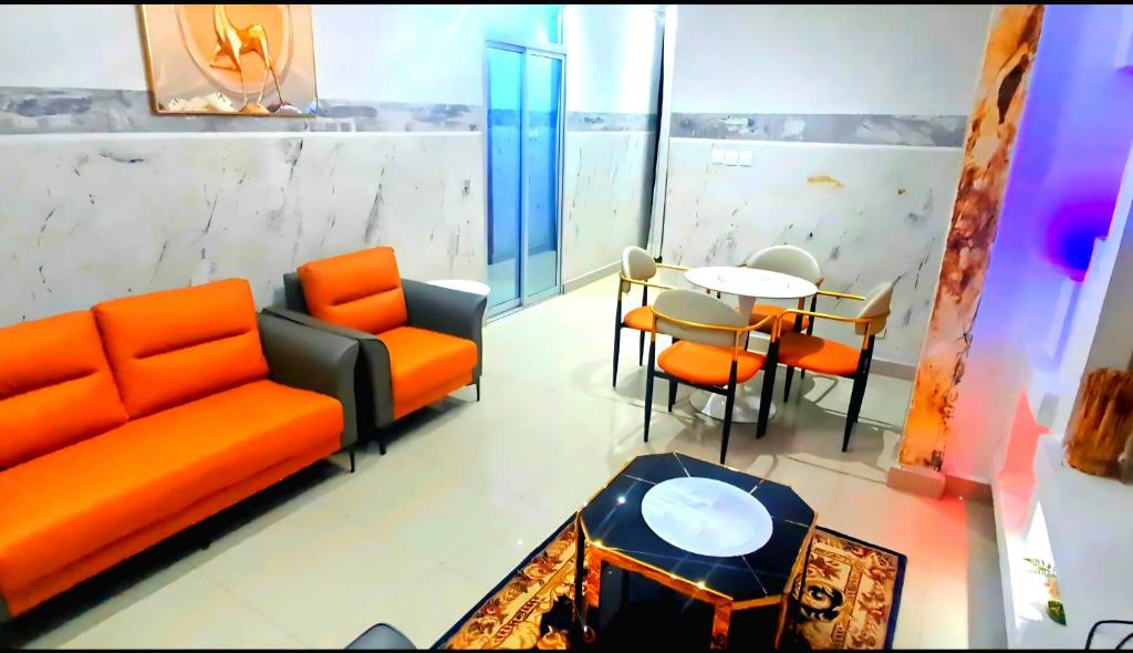 a living room with an orange couch and a table at Skyline Guest House in Kinshasa
