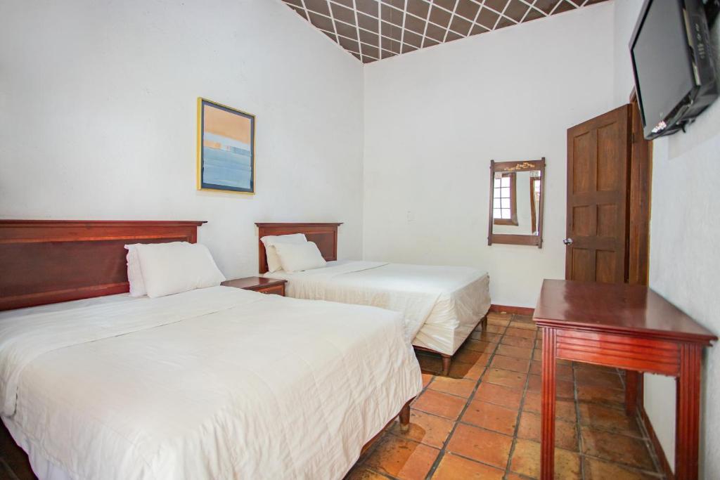 a hotel room with two beds and a television at Hotel Urdiñola Saltillo in Saltillo