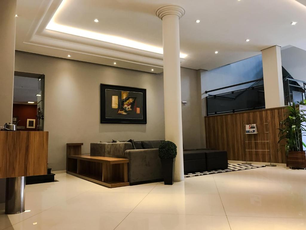 a lobby with a couch and a tv on the wall at Rede Andrade Mercado Hotel in Curitiba