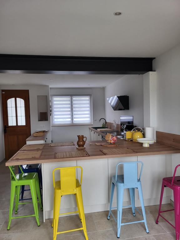 a kitchen with colorful chairs around a kitchen counter at Les Oyats in Équihen-Plage