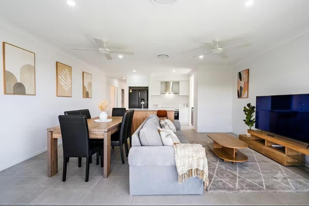 a living room with a couch and a table and a television at Kinma Valley Retreat KVR in Morayfield