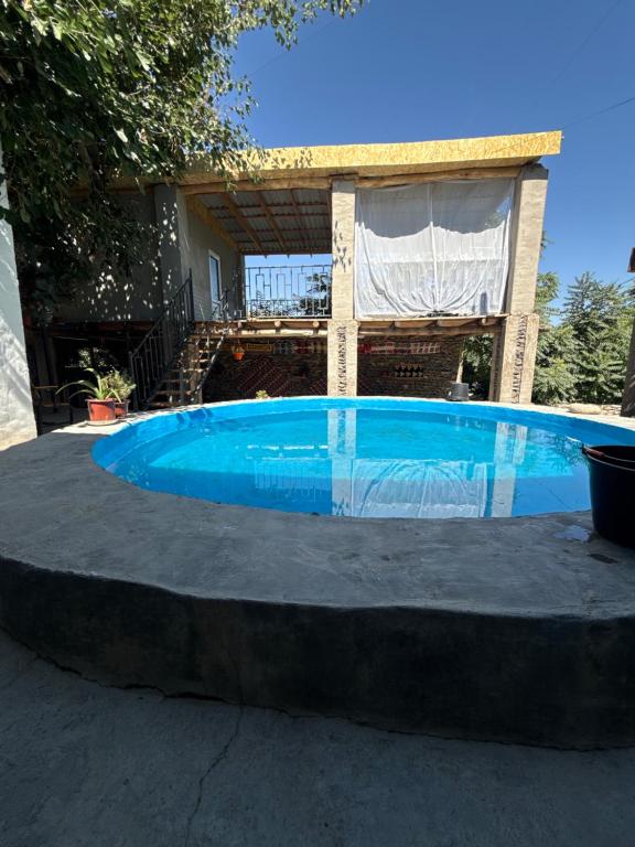 a large blue swimming pool in front of a house at Sentyab Obi chashma guest house in Tadzhimi