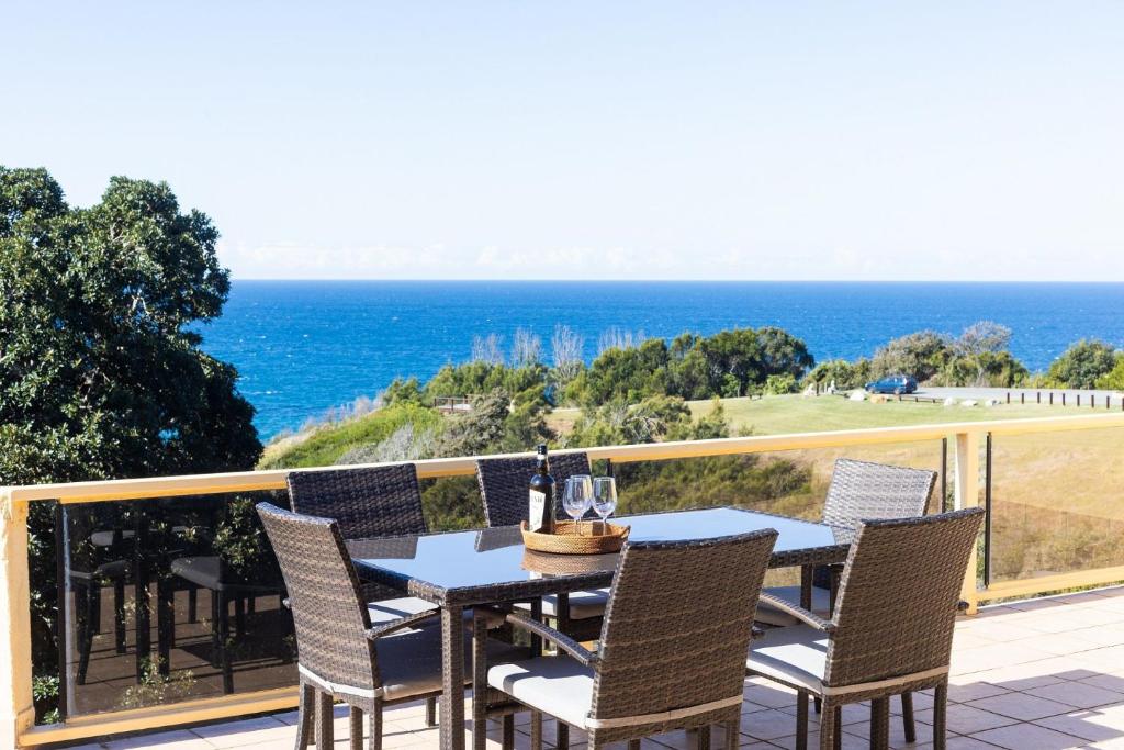a table and chairs on a balcony with the ocean at Coastal Chill in Nambucca Heads