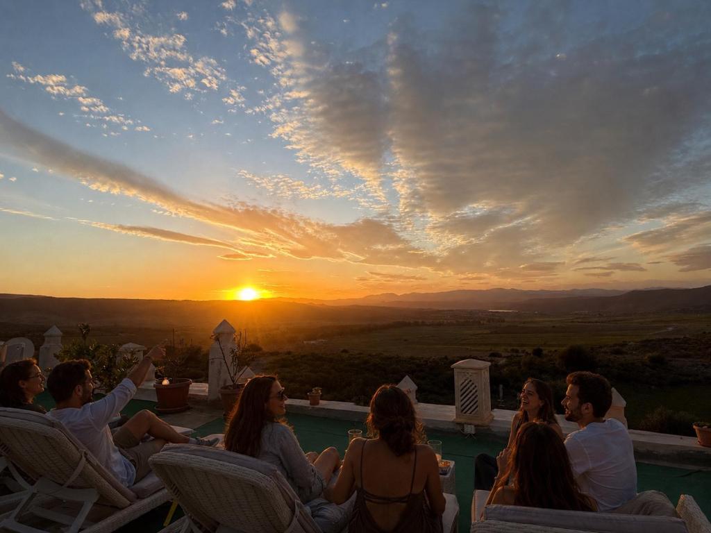 a group of people sitting around a pool watching the sunset at Under Stars in Nebeur