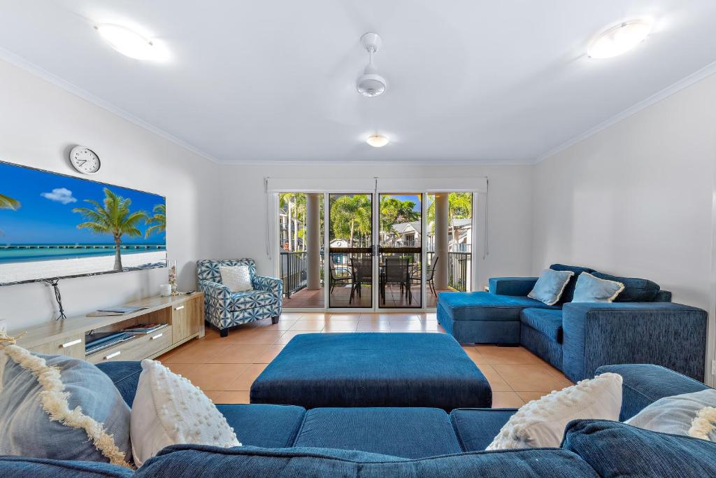 a living room with blue couches and a tv at Beach Court - Airlie Beach in Airlie Beach