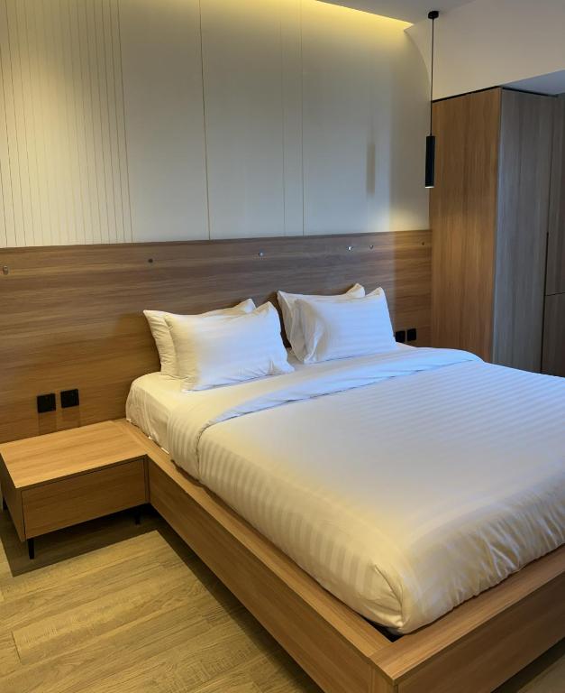 a bed with white sheets and pillows in a room at Hamsun DHA in Karachi