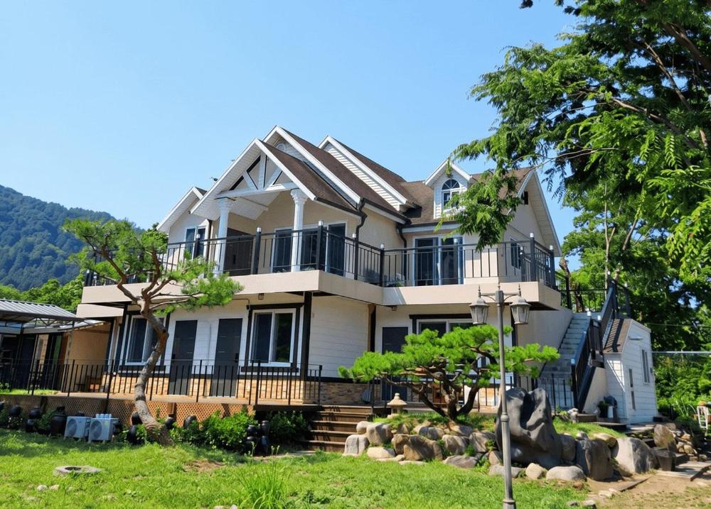 a large white house with a balcony and trees at Gapyeong Yunseul Pension in Chuktul-li