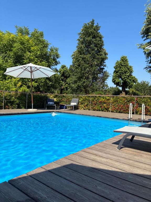 a swimming pool with a table and an umbrella at Casa la Mirage 6 in Bozzolo