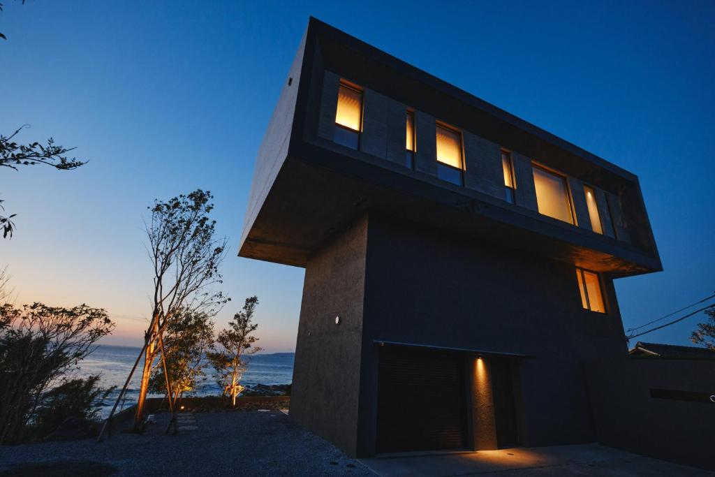 a black house with lit windows at dusk at THE THIRD PLACE tatéyama 楼 in Tateyama