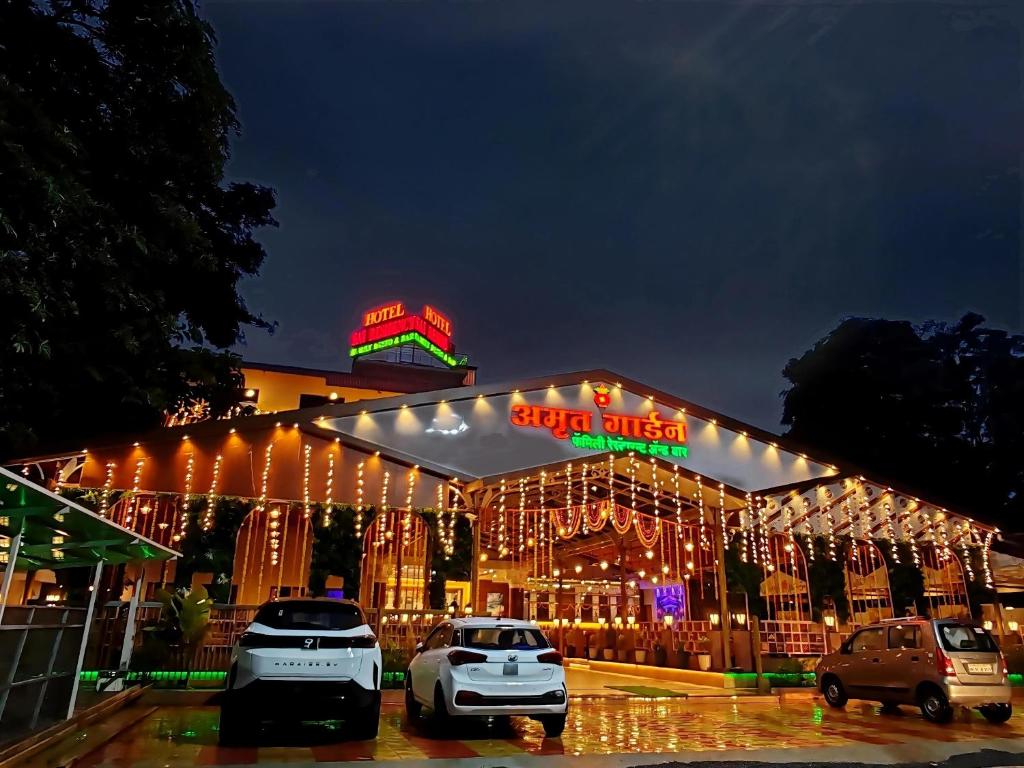 a building with cars parked in a parking lot at Hotel Sai Residency in Karjat
