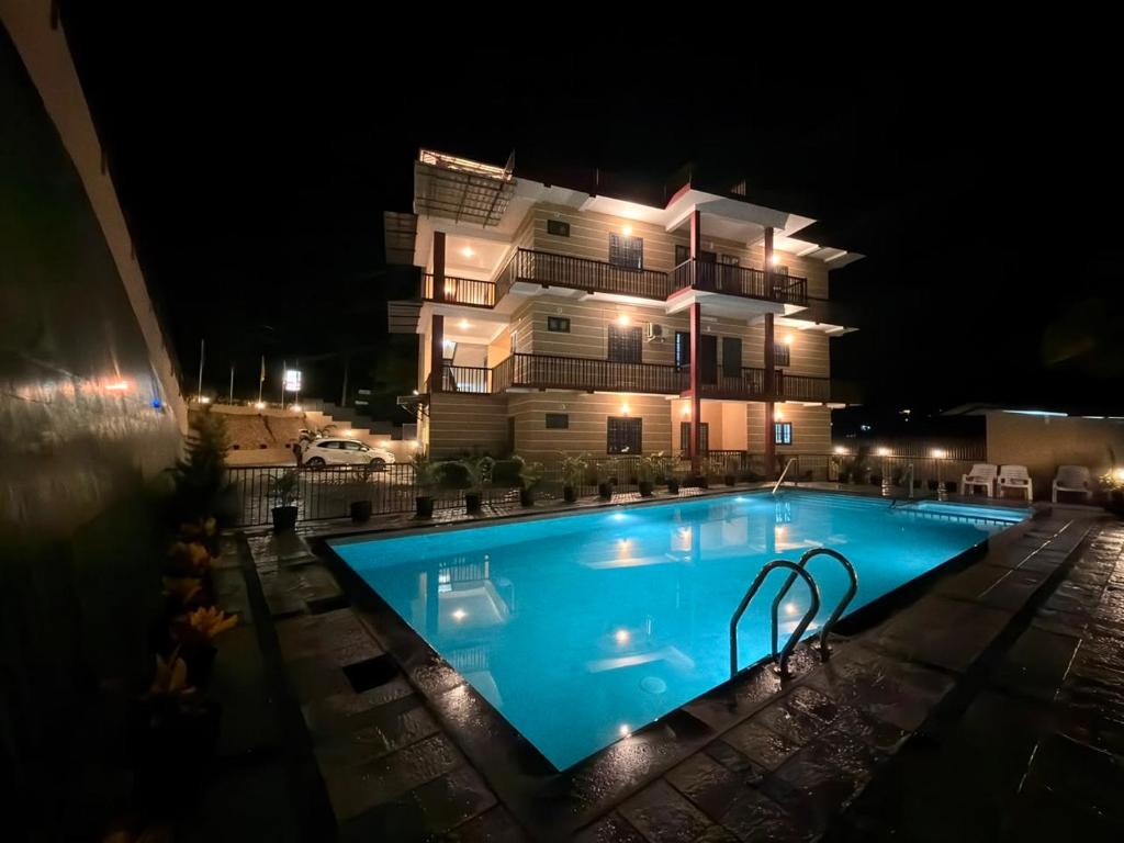 a swimming pool in front of a building at night at The Rosetta Inn, Wayanad in Wayanad