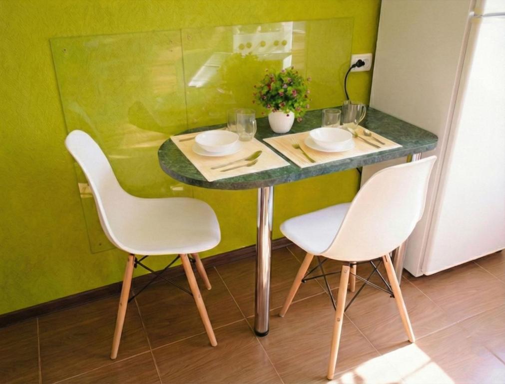 a table with two white chairs and a green counter top at Poltava Green Apartments in Poltava
