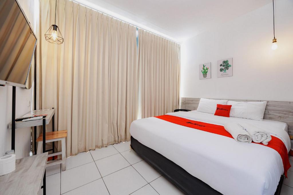a hotel room with a large bed and a television at RedDoorz near Mangga Dua Mall in Jakarta