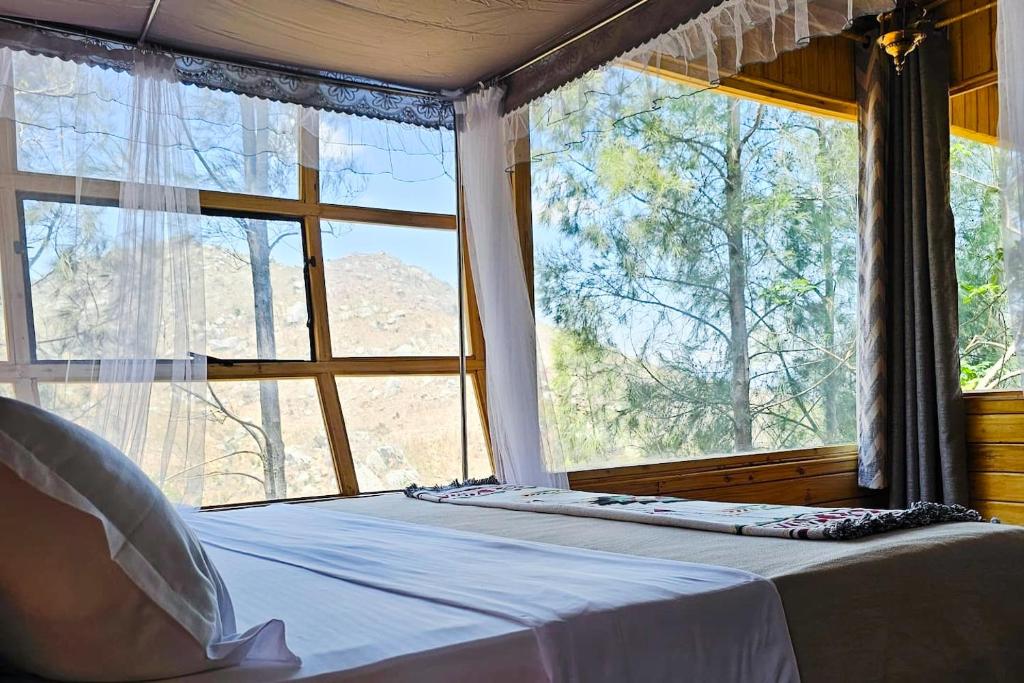 a bedroom with a bed and a large window at Hidden Cabin in Iringa