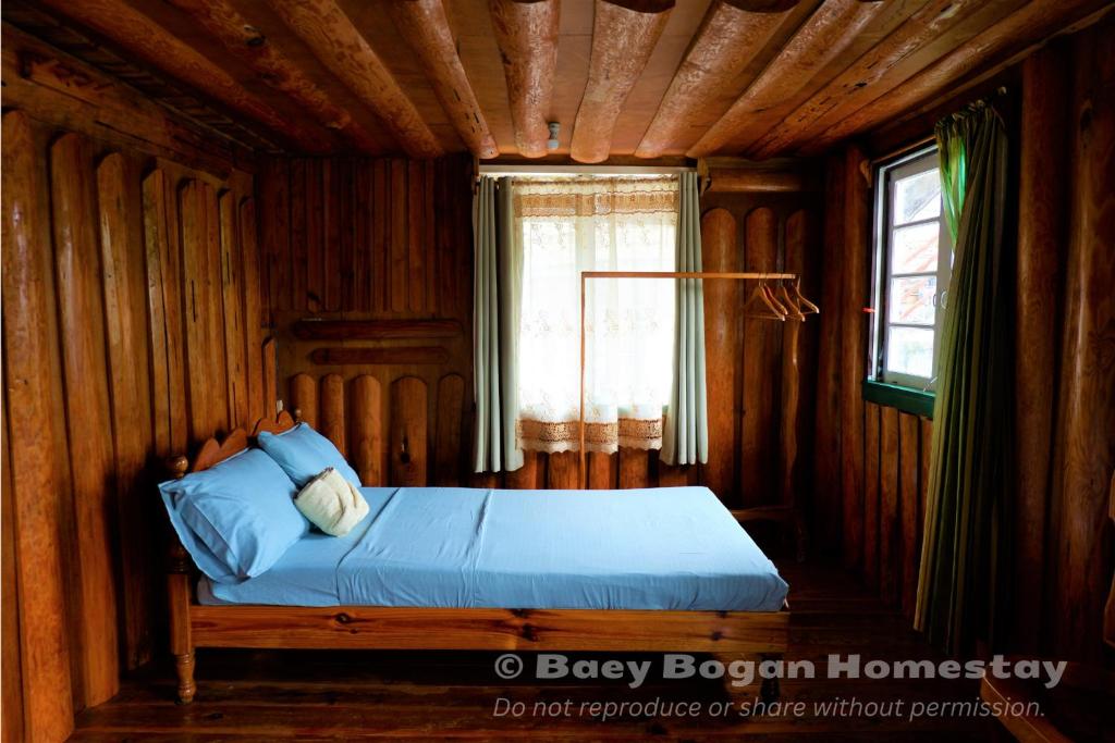 a bed in a wooden bedroom with a window at Baey Bōgan Homestay in Sagada