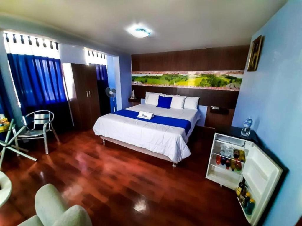 a bedroom with a large bed with blue walls and wooden floors at Hotel Inkas in Arequipa