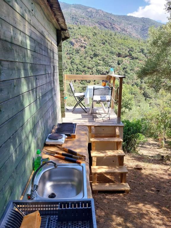 a deck with a sink and a table and a chair at Small chalet in Serriera