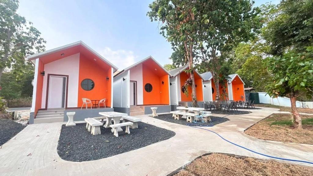 an orange and white house with picnic tables in front of it at ปลายเขื่อนแคมปิ้ง บ้านวิวเขื่อน in Sirindhorn