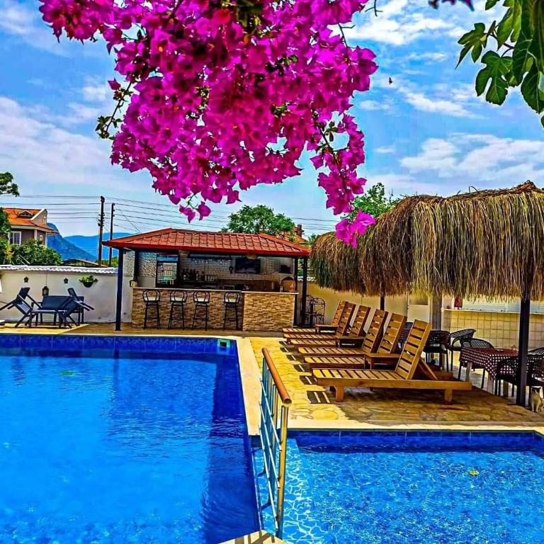 a resort with a swimming pool with chairs and pink flowers at Garden-view suite room in Ortaca