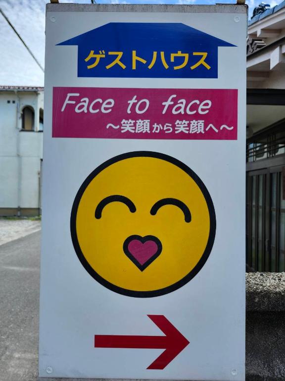 a sign for a face to face sign with an arrow at Guesthouse Face to Face in Fujinomiya