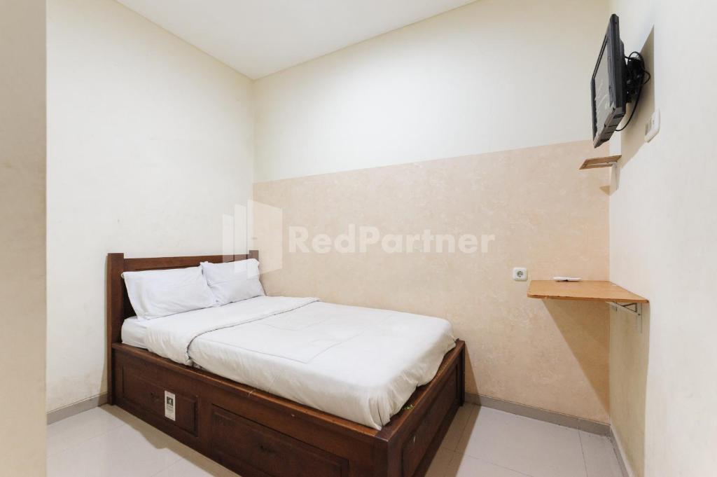 a bed in a room with a tv on a wall at Nipa Guest House near Universitas Widyagama Mitra RedDoorz in Blimbing