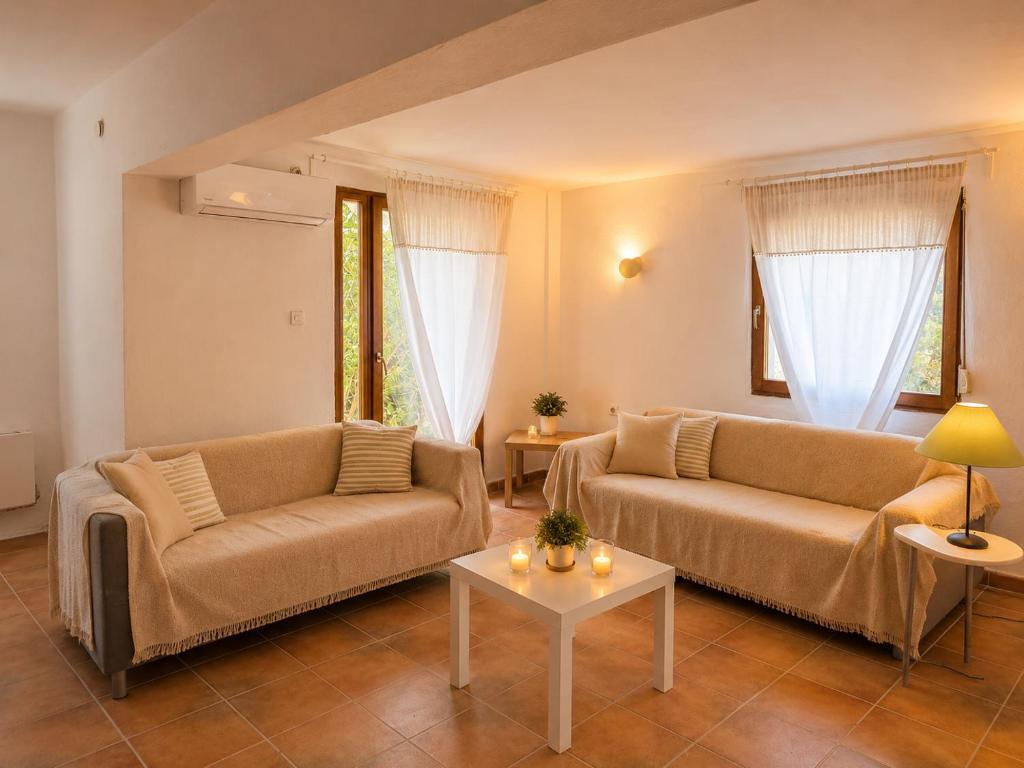 a living room with two couches and a table at Natasa private garden apartment in Polychrono
