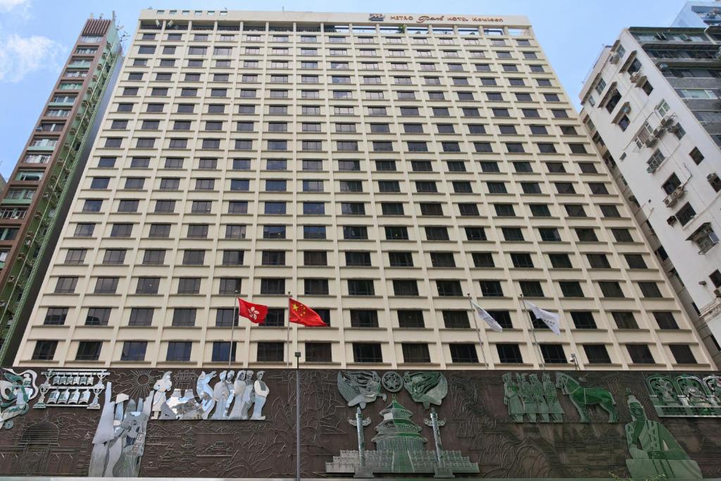 a tall building with flags in front of it at Metropark Hotel Kowloon Hong Kong in Hong Kong
