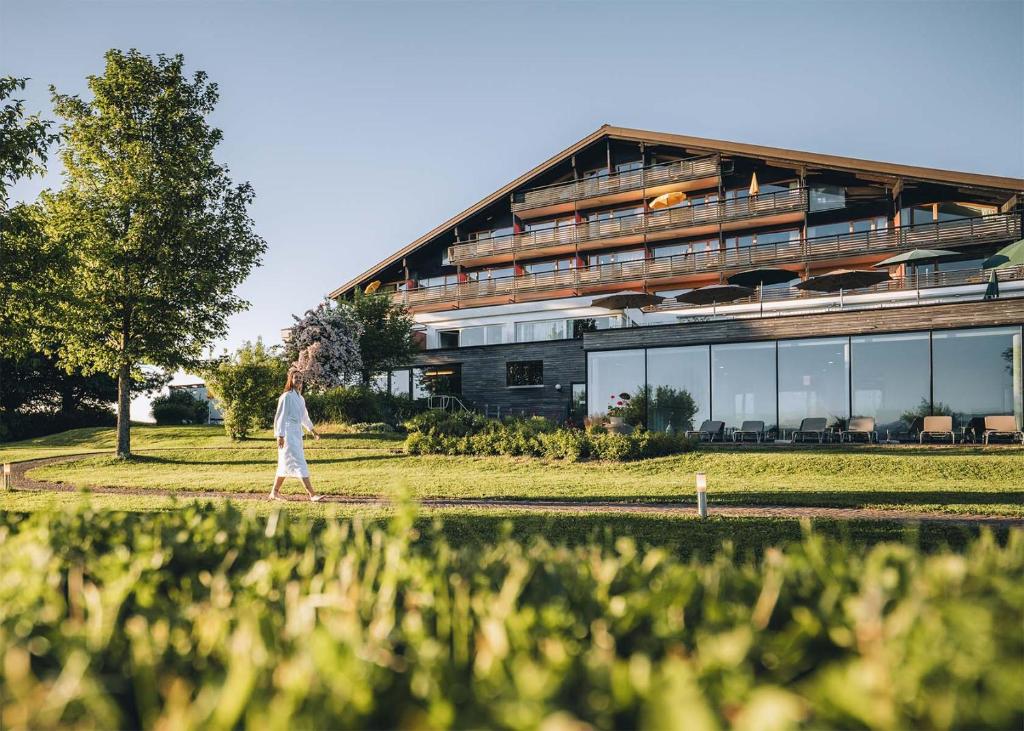 a woman walking in front of a building at Wellnesshotel Linde in Sulzberg