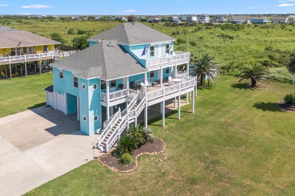 an aerial view of a blue house with a porch at 3 King Suites 15 Guests - Sunzout in Bolivar Peninsula