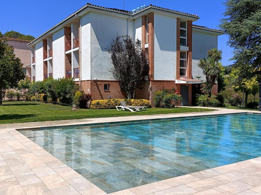 a house with a swimming pool in front of a building at Hotel Sausa in Vilafreser